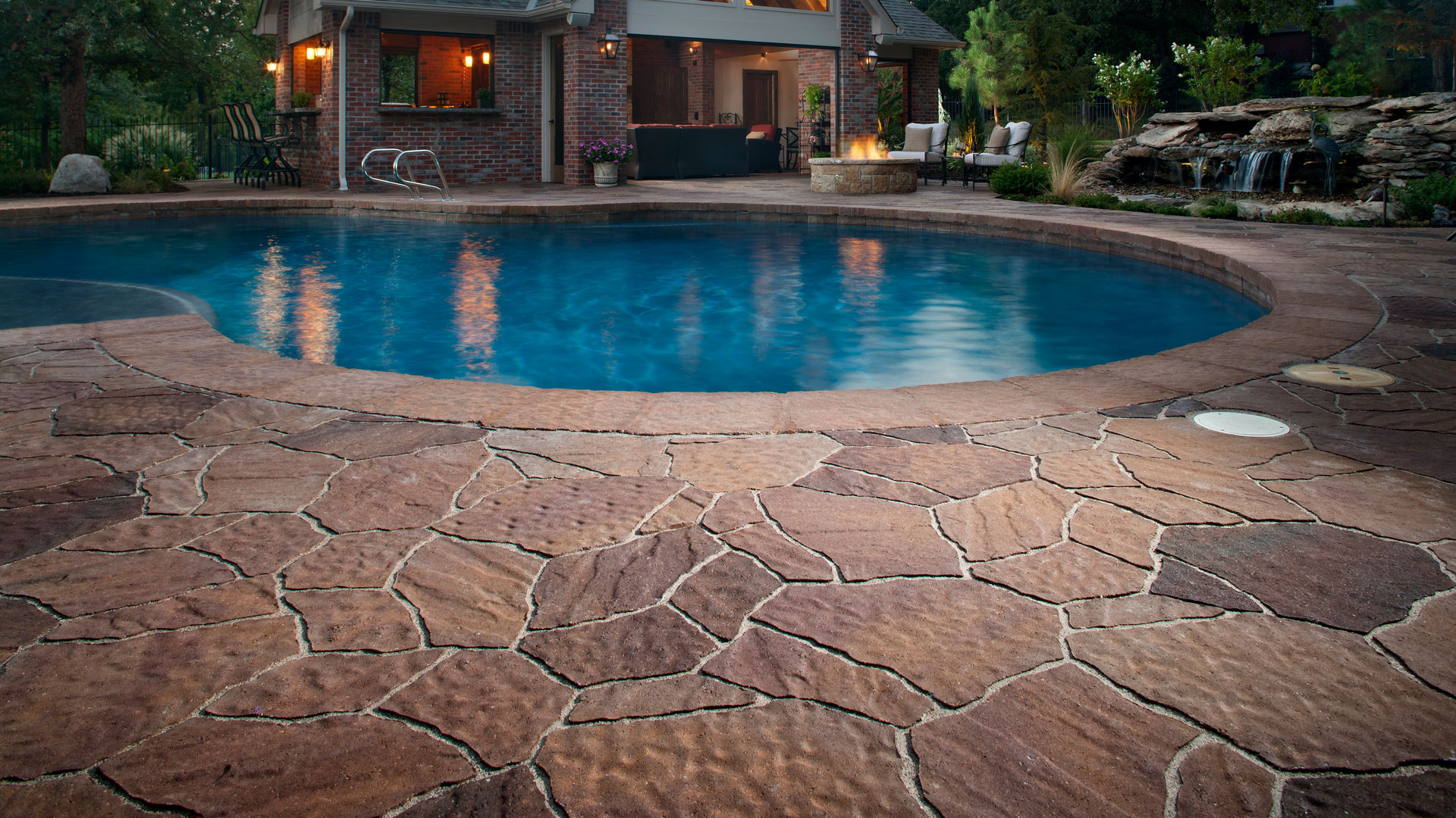 Beautiful stone pavers next to pool with house in the background