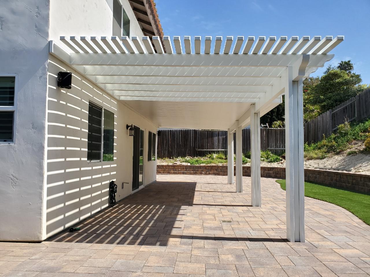 Concrete pavers and outdoor structure next to artificial turf in backyard